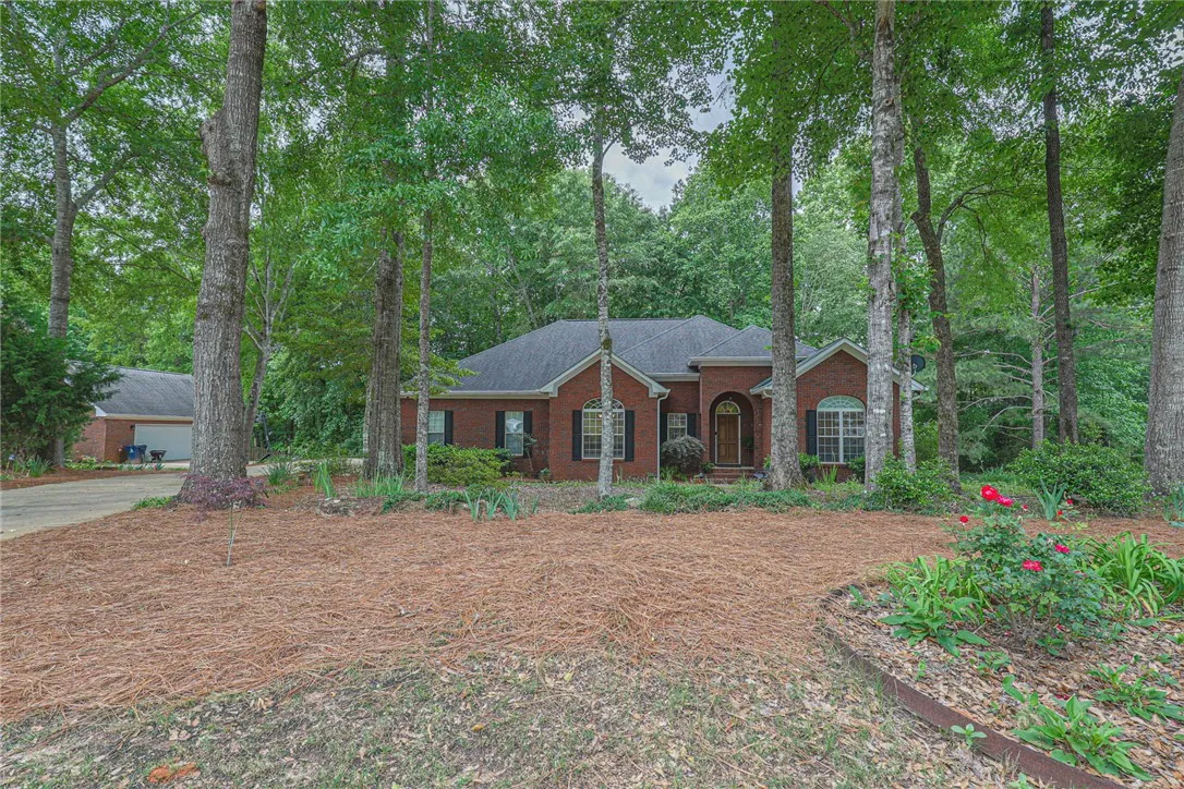 Mature trees frame this traditional brick home with an attached garage.
