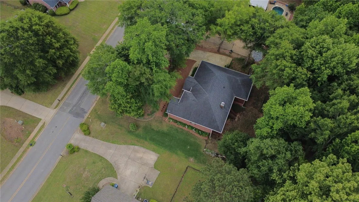 An aerial perspective reveals a private residence nestled amongst lush, mature trees and ample green space.