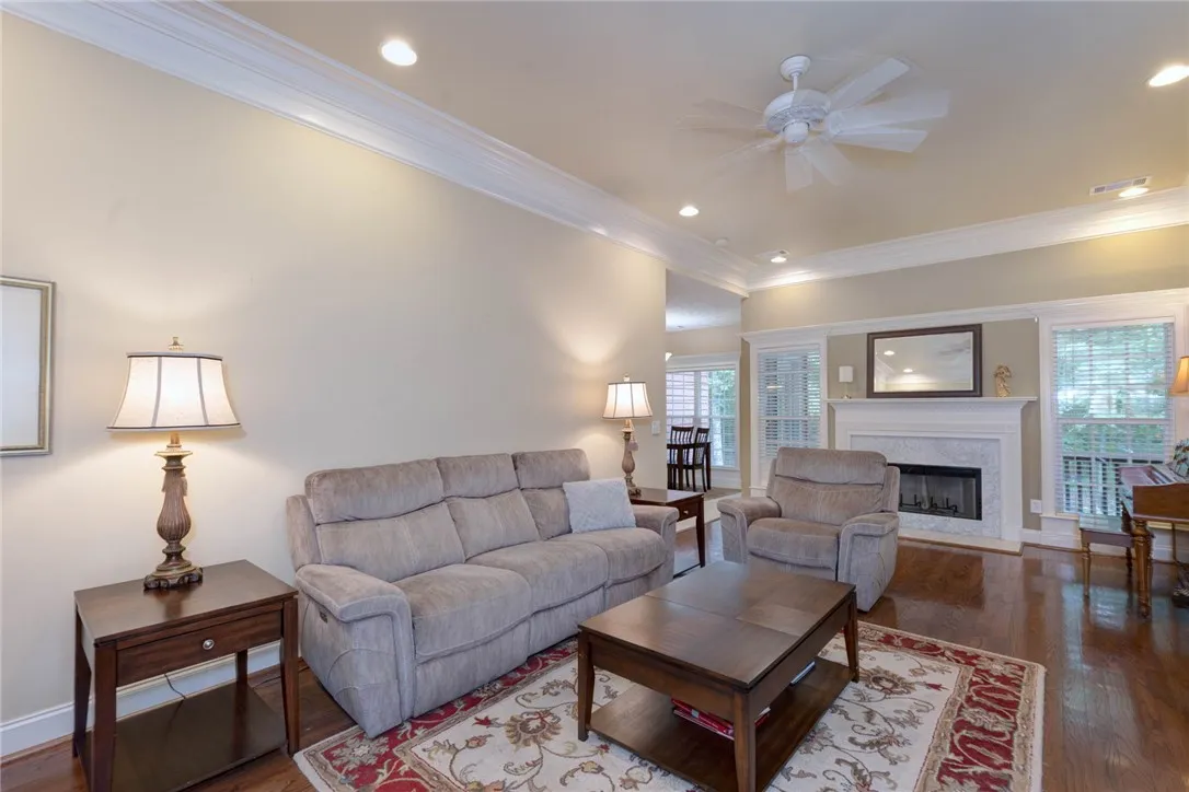 Hardwood floors and a welcoming fireplace create an inviting atmosphere in this well-lit living room.