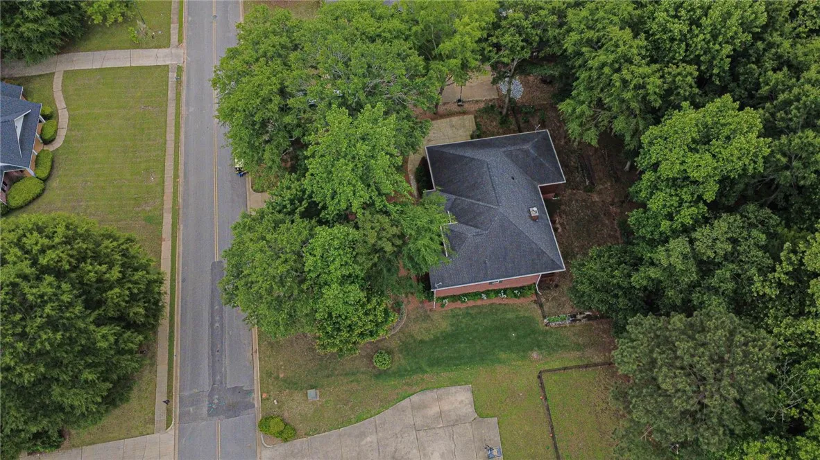 An aerial perspective reveals a private residence nestled amidst mature trees with a well-maintained lawn.