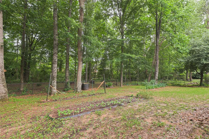 A verdant backyard offers a fenced garden and mature trees.