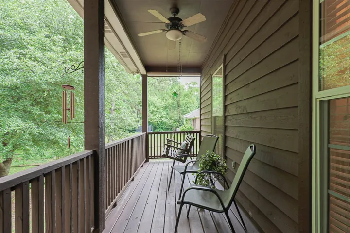 A spacious covered porch invites relaxation with a wooden deck and ceiling fan.
