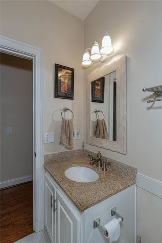 A well-appointed bathroom features a single vanity with a granite countertop and bright overhead lighting.