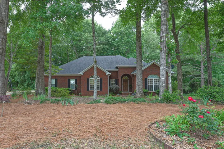 A classic brick exterior residence, nestled amidst mature trees, offers a welcoming facade and tranquil surroundings.