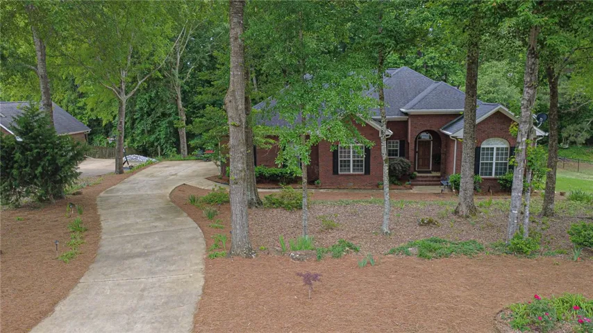 A graceful curved driveway leads to this classic brick residence, nestled amidst mature trees and verdant landscaping.