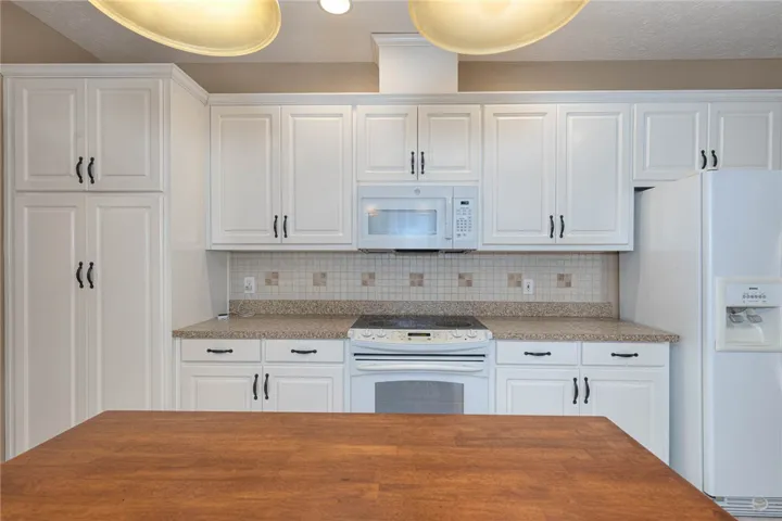 White cabinetry and appliances create a clean aesthetic in this well-appointed kitchen.