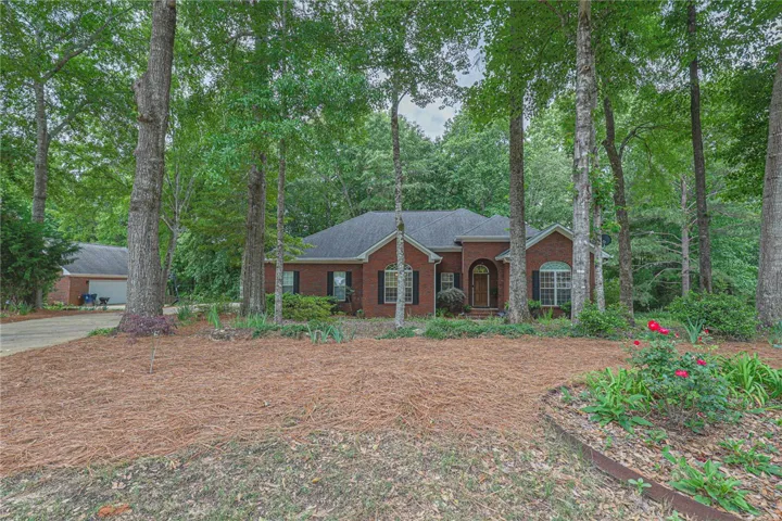 Mature trees frame this traditional brick home with an attached garage.