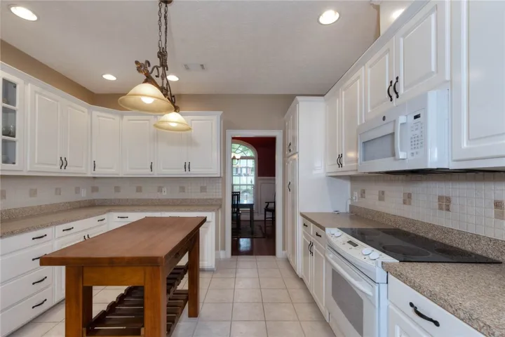 A well-lit kitchen with pristine white cabinetry, offering generous counter space and an inviting central island.