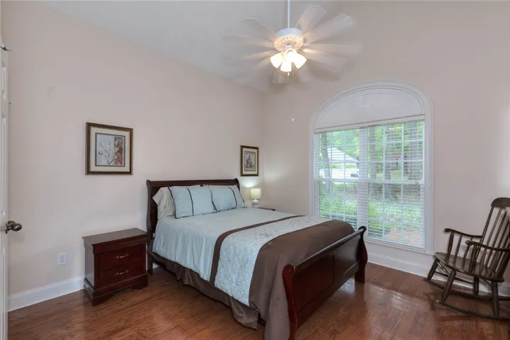 Hardwood floors and a grand arched window grace this comfortable bedroom.