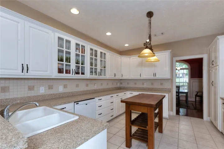 White cabinetry, solid surface counters, and tile flooring define this well-appointed culinary space.