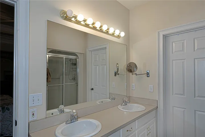 Double vanity in a primary bath, showcasing a spacious mirror and convenient shower access.