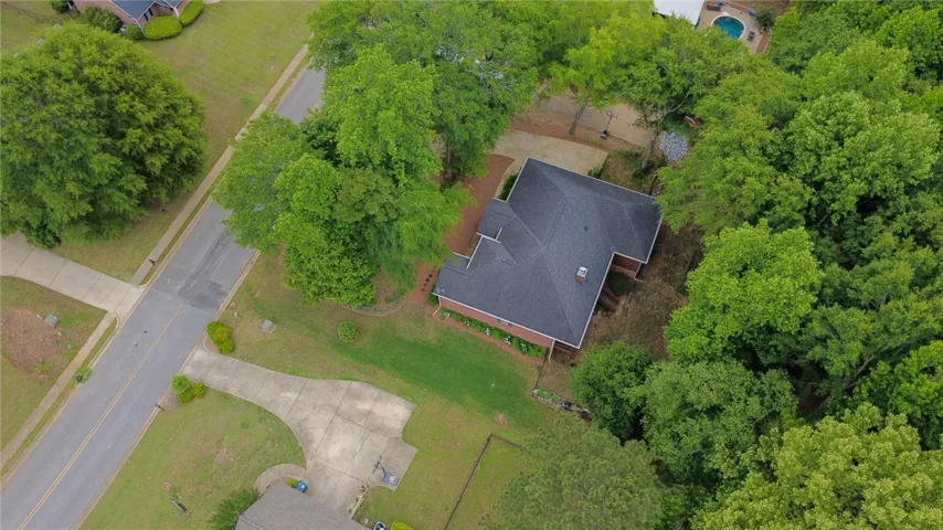 Aerial view showcasing a residential property nestled amongst verdant trees with a dark roof.