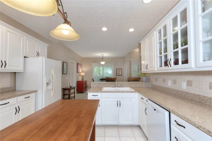 A well-lit kitchen with ample counter space and white cabinetry seamlessly connects to a dining area.