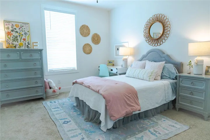 A well-lit bedroom provides a serene retreat, offering ample space and soft carpeting.