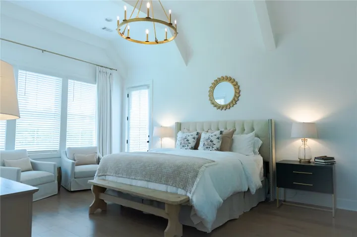 A vaulted ceiling crowns this generously sized sleeping space, illuminated by a chic chandelier.