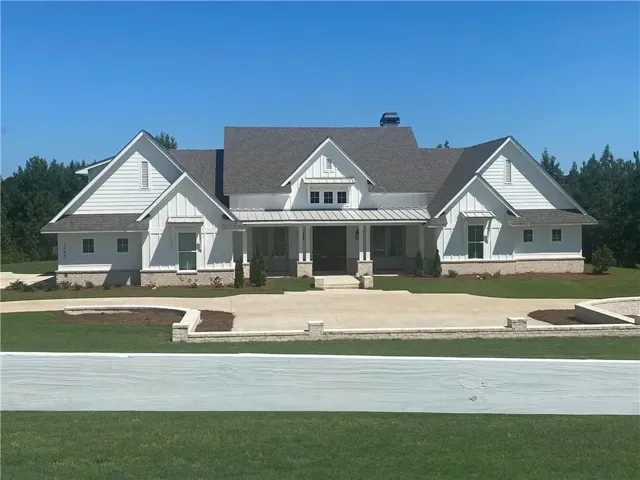 Impressive gabled rooflines define this elegant, modern farmhouse with a wide front porch and brick accents.