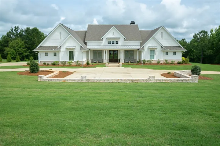 A grand white home awaits, framed by lush greenery and a sweeping circular drive.