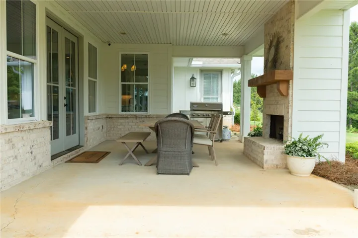 An inviting outdoor living area features a covered patio with a built-in fireplace and comfortable seating.