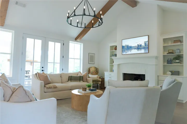 Sun-filled living space features exposed beam ceilings, a central fireplace, and built-in shelving.