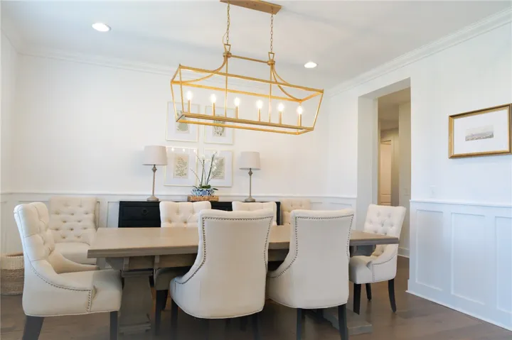 A refined dining space features a golden chandelier above a sturdy table, with wainscoting adorning the walls.