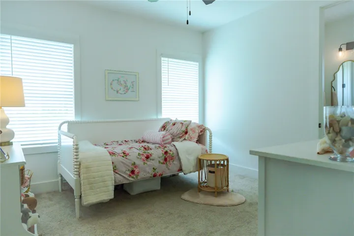 This tranquil bedroom offers soft carpeting and ample natural light through well-lit windows.
