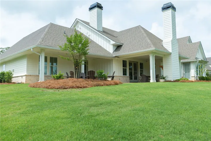 A broad, green lawn perfectly complements the home's covered patio, offering an ideal setting for outdoor enjoyment.