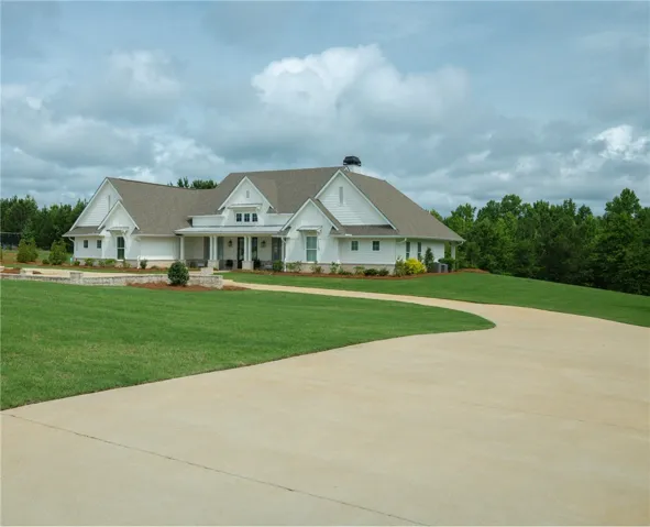 A graceful home with a welcoming front porch and extensive, verdant lawns.