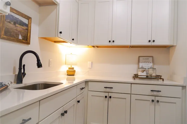 Ample counter space and crisp white cabinetry define this well-appointed laundry area.
