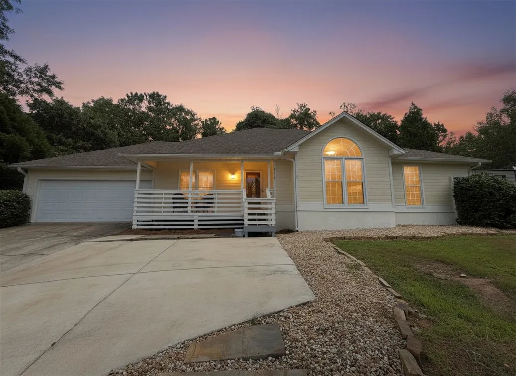 A welcoming facade with a covered porch and an integrated garage, set against a vibrant twilight sky.
