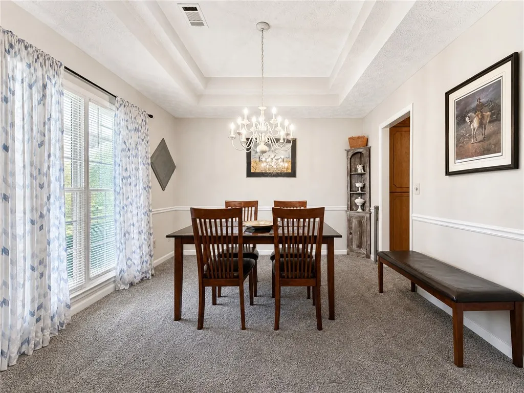Elegant tray ceilings and plush carpeting define this spacious dining room.