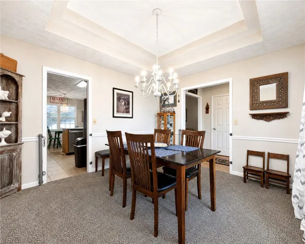 A classic dining room features a refined tray ceiling and elegant chandelier, setting the scene for memorable meals.