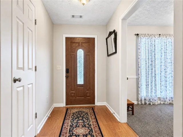 A welcoming front entry features natural wood flooring leading to a decorative glass-paneled door.