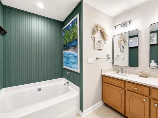Relax in this tranquil bathing space, featuring a classic tub and an elegant vanity.