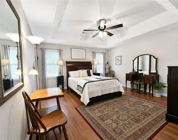 A spacious sleeping area with lustrous wood flooring and a classic tray ceiling design.