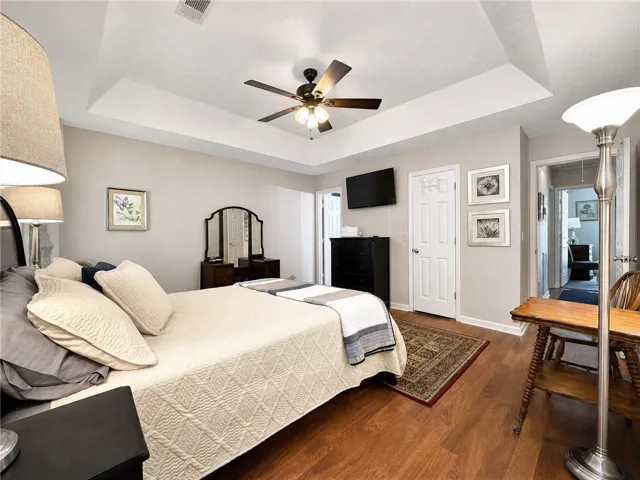 Hardwood floors and a tray ceiling create a peaceful retreat in this primary bedroom.