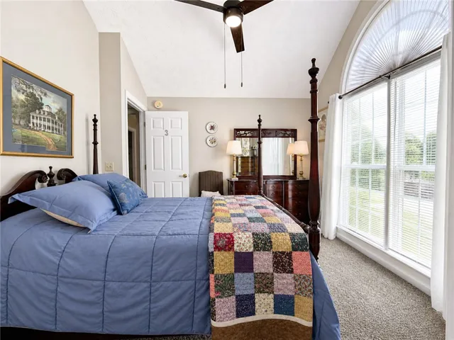An inviting bedroom with vaulted ceilings and ample natural light from the large arched window.