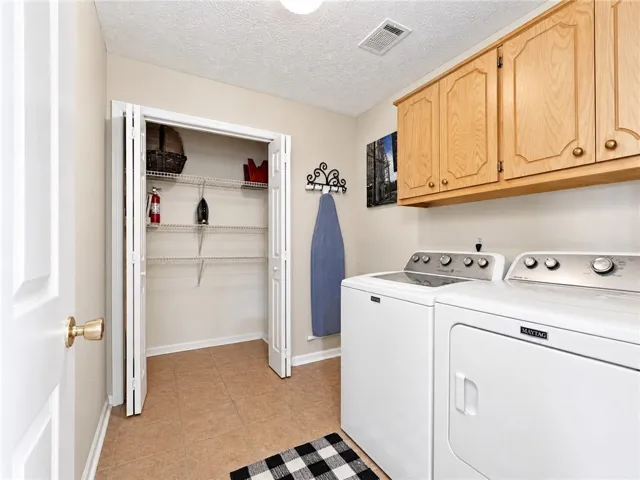 Functional laundry room offers upper cabinetry for storage and efficient washer and dryer units.