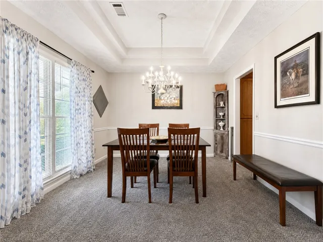 Elegant tray ceilings and plush carpeting define this spacious dining room.