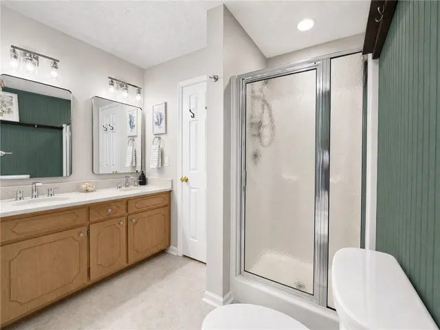 Dual vanities and a glass-enclosed shower create a practical and refreshing bathroom space.