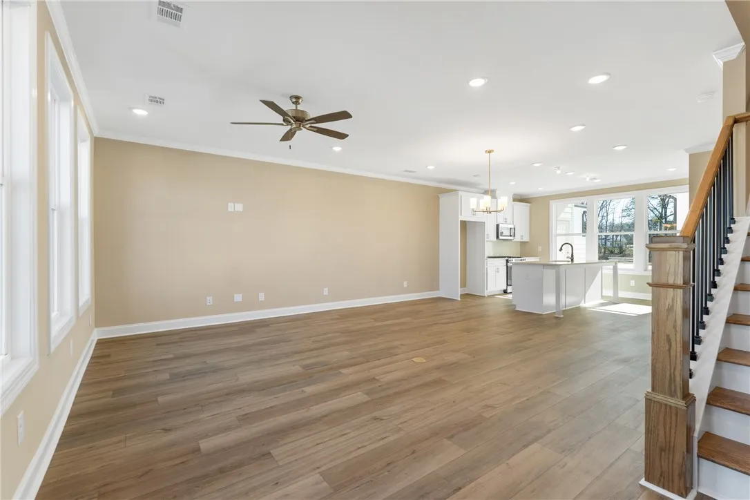 A spacious, open-concept interior featuring light hardwood flooring and a functional kitchen island. Photos are not of subject property. Photos are of the same floorplan of a completed home.