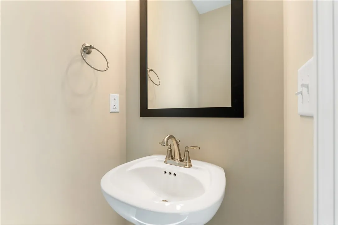 A well-appointed pedestal sink and mirror elevate this compact powder room. Photos are not of subject property. Photos are of the same floorplan of a completed home.