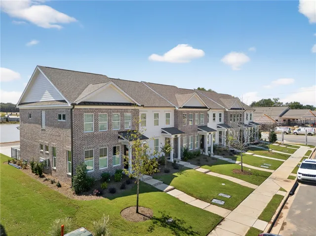 Rows of attractive townhomes feature well-maintained lawns and sidewalks. Photos are not of subject property. Photos are of the same floorplan of a completed home.