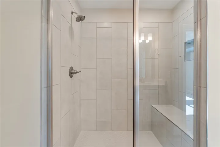 Modern shower with sleek tiled walls and a convenient built-in bench. Photos are not of subject property. Photos are of the same floorplan of a completed home.