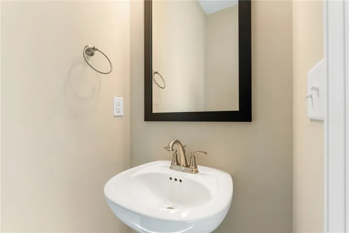 A well-appointed pedestal sink and mirror elevate this compact powder room. Photos are not of subject property. Photos are of the same floorplan of a completed home.