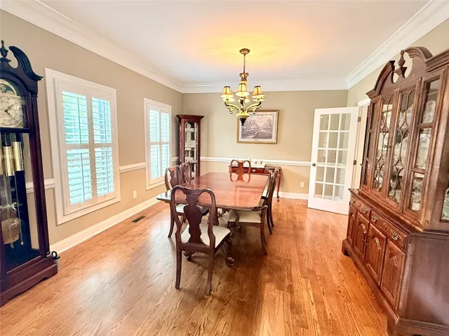 A refined dining space awaits, featuring gleaming hardwood floors and elegant crown molding.