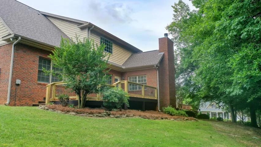 A classic brick exterior meets a spacious wooden deck overlooking the verdant backyard.