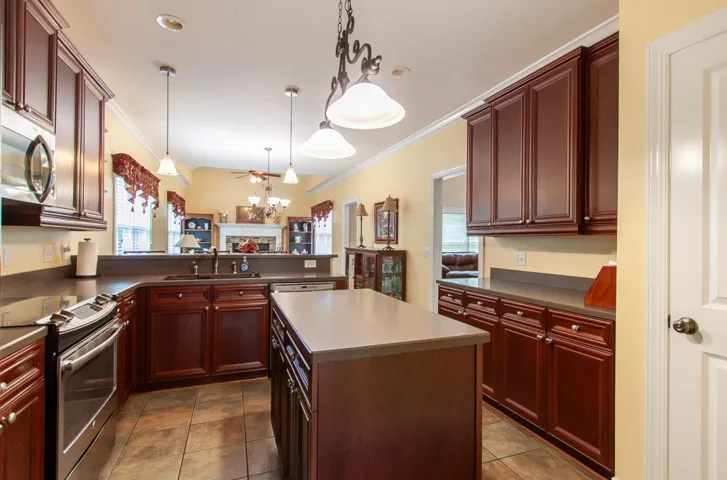 A well-appointed kitchen features rich cabinetry, practical island, and views to the living area.