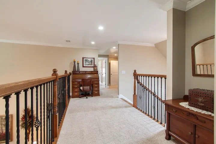 A well-lit landing area provides a flexible space for an office or study, complete with elegant wood and iron railings.