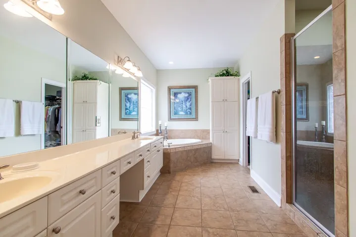 Indulge in a tranquil retreat featuring a soaking tub, dual vanities, and a tiled shower.