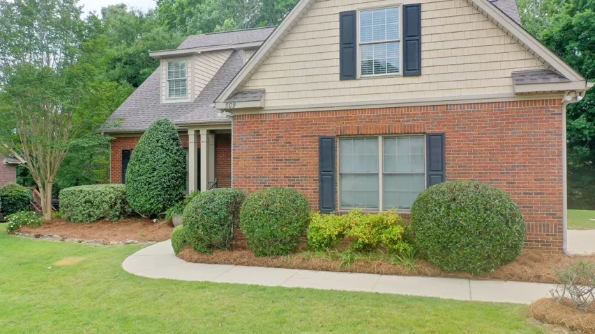 Well-maintained landscaping frames the brick and shingle exterior of this charming residence.